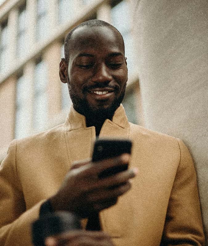 man looking down at phone smiling