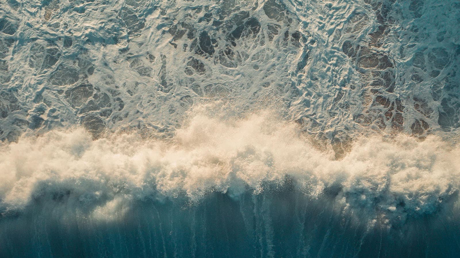 Aerial of ocean waves crashing into beach